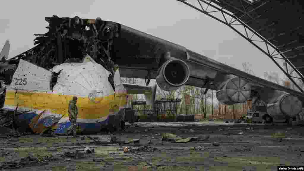 Украинский солдат проходит мимо обломков транспортного самолета Ан-225 "Мрия", 2 апреля 2022 года. Самолет "Мрия" был самым большим самолетом в мире, его уничтожили российские военные 27 февраля во время боев на аэродроме Антонов в Гостомеле. "Мрия", что означает "мечта" или "вдохновение", полюбилась любителям авиации всего мира.