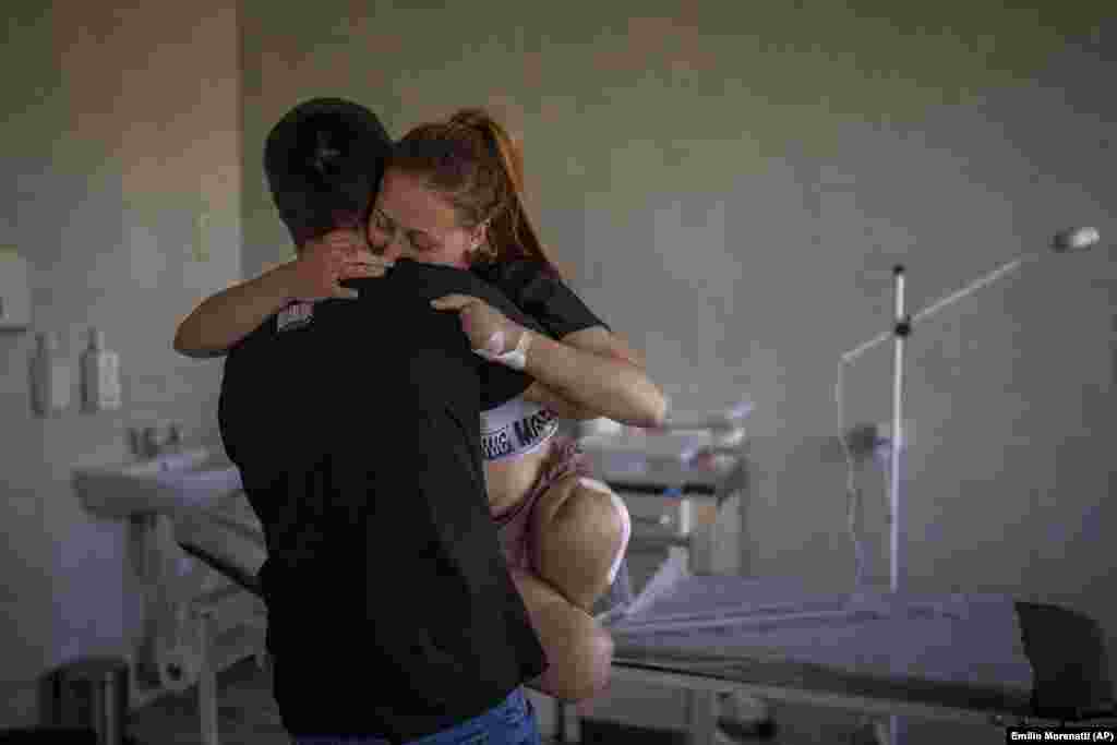 Оксана Баладина, 23 года, на руках у мужа Виктора в больнице во Львове, 13 мая 2022 года. Оксана потеряла обе ноги и четыре пальца на левой руке из-за взрыва гранаты. "Произошел взрыв. Сразу после этого я почувствовала, что мои ноги проваливаются в пустоту. Я пыталась осмотреться и увидела, что у меня больше нет ног — только кости, плоть и кровь", — вспоминала она.