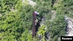 Un stop-cadru dintr-un videoclip difuzat de Ministerul Apărării rus arată un soldat rus care ridică steagul la Iablunivka, în regiunea Donețk. Rușii anunță des că au mai cucerit sate în zona respectivă. 