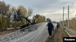 Українські військовослужбовці встановлюють антидронові сітки над дорогою поблизу Добропілля в Донецькій області, 8 жовтня 2025 року